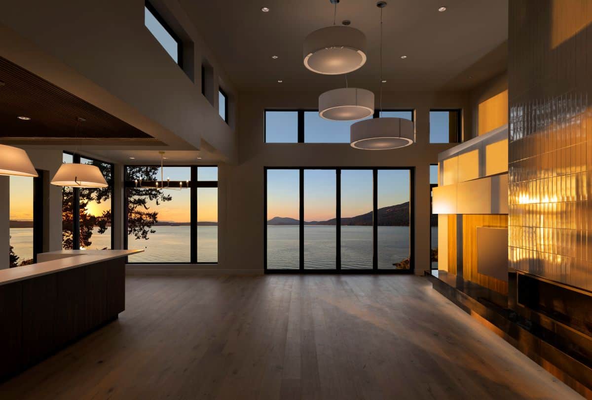 Bright modern interior with large windows overlooking water at sunset, Victoria BC.
