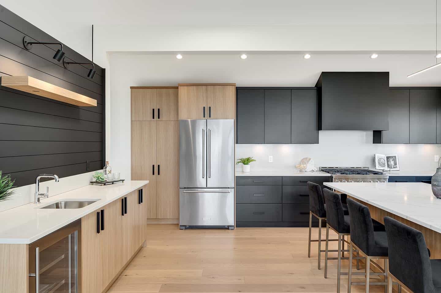 Modern kitchen with light wood and dark cabinets, stainless steel appliances and island.