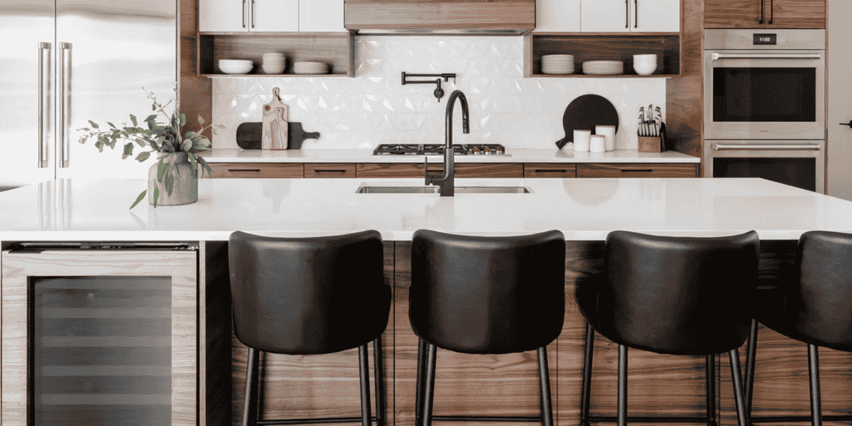 Modern kitchen with island, white cabinets, and black bar stools.