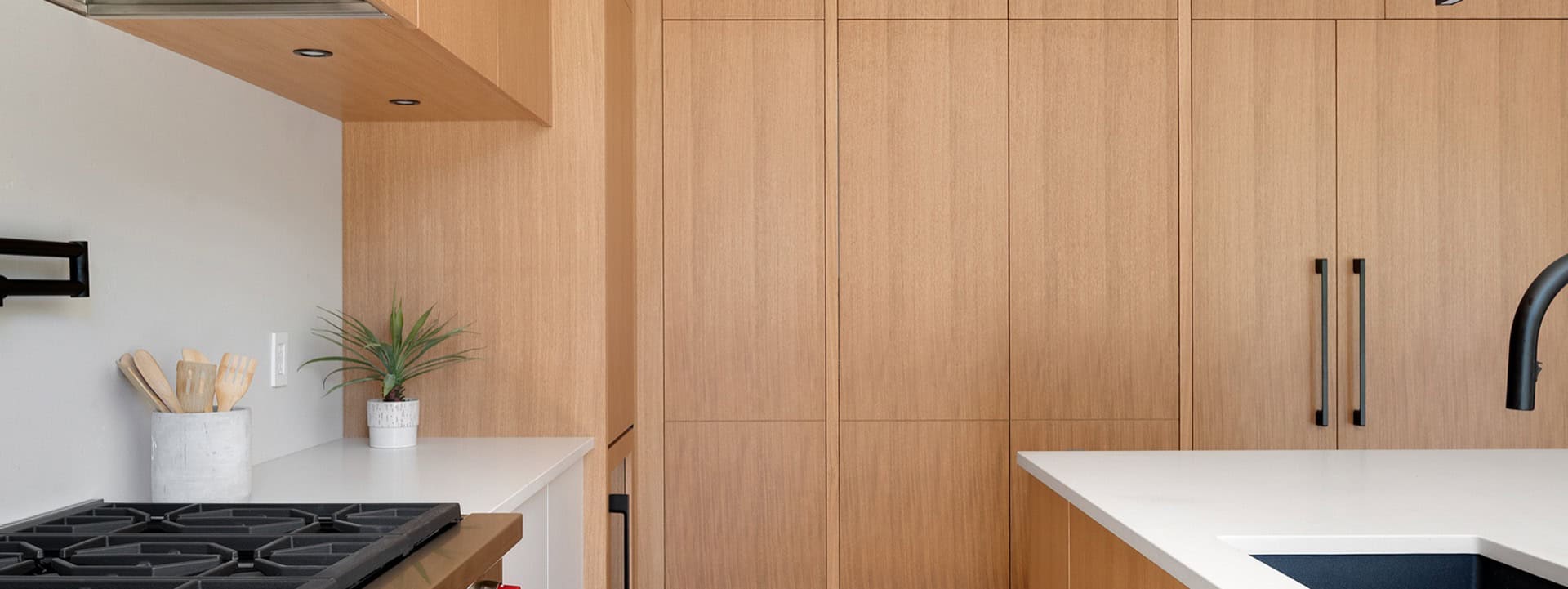 Modern kitchen with light wood cabinets and white countertop by White Wolf Homes.