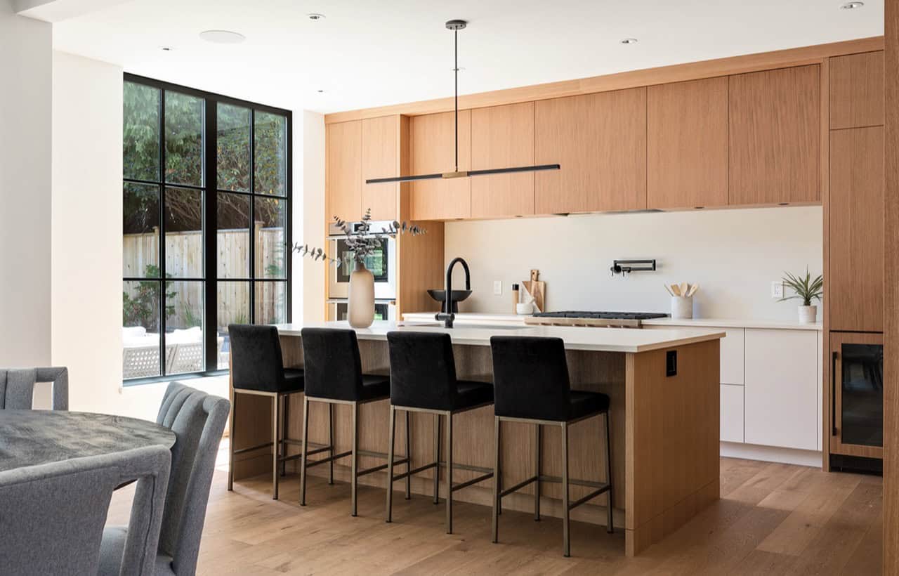 Modern kitchen with wooden cabinetry, large island, and black bar stools in Victoria BC home.