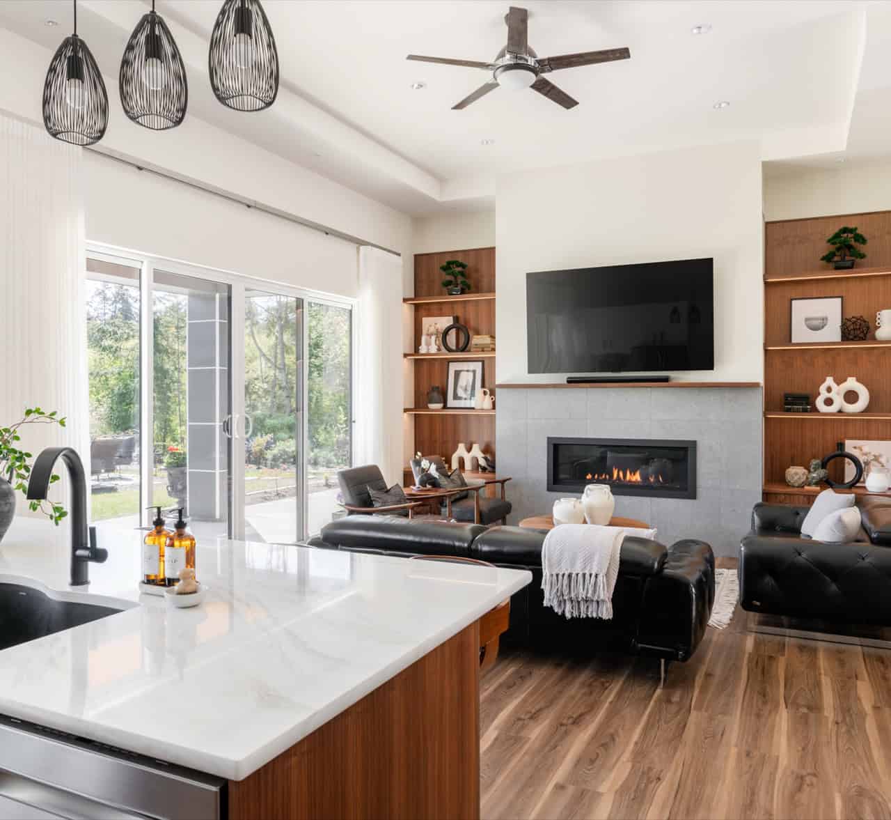 Bright open living room with large windows, built-in shelves, and a wall-mounted TV above a sleek, 2.