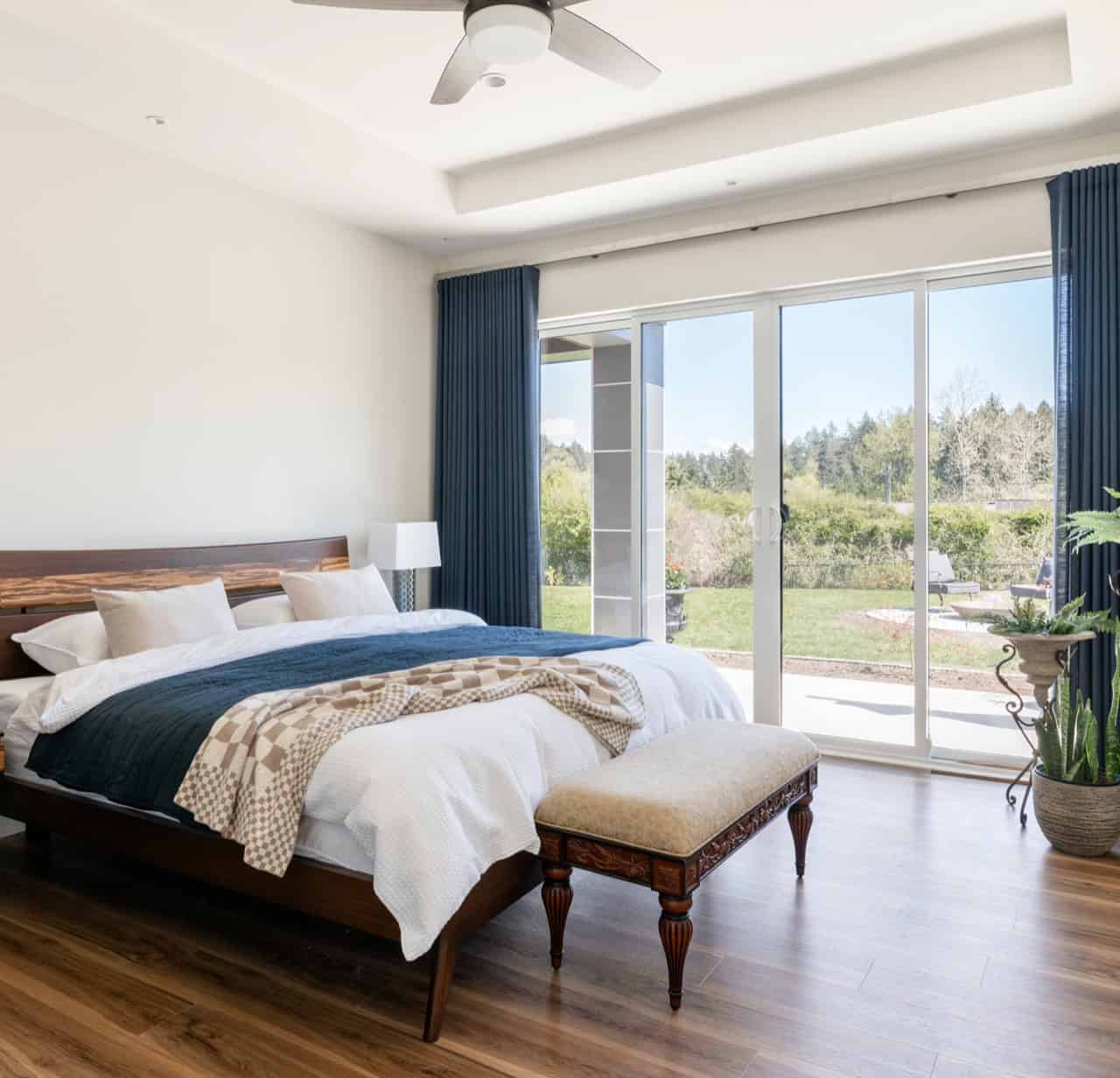 Spacious master bedroom with large glass doors to a patio and landscaped yard, contemporary queenly:.