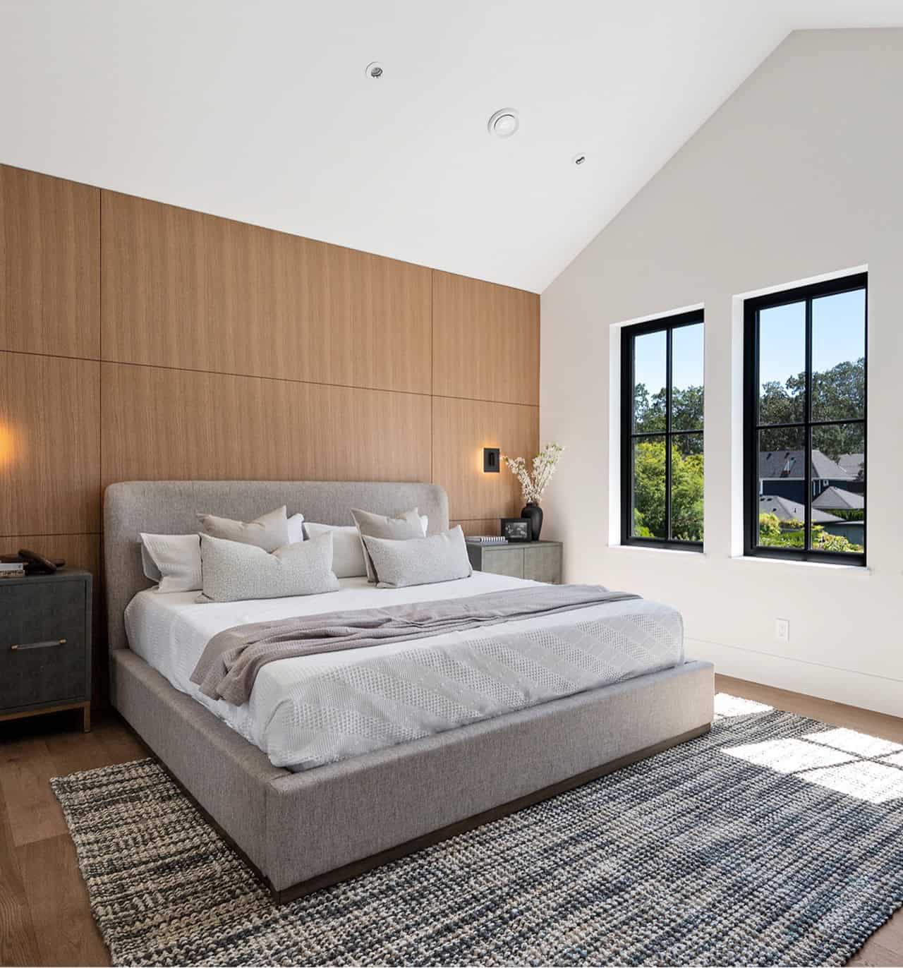 Modern bedroom in a custom home by White Wolf Homes in Victoria BC with large windows and wooden alc.
