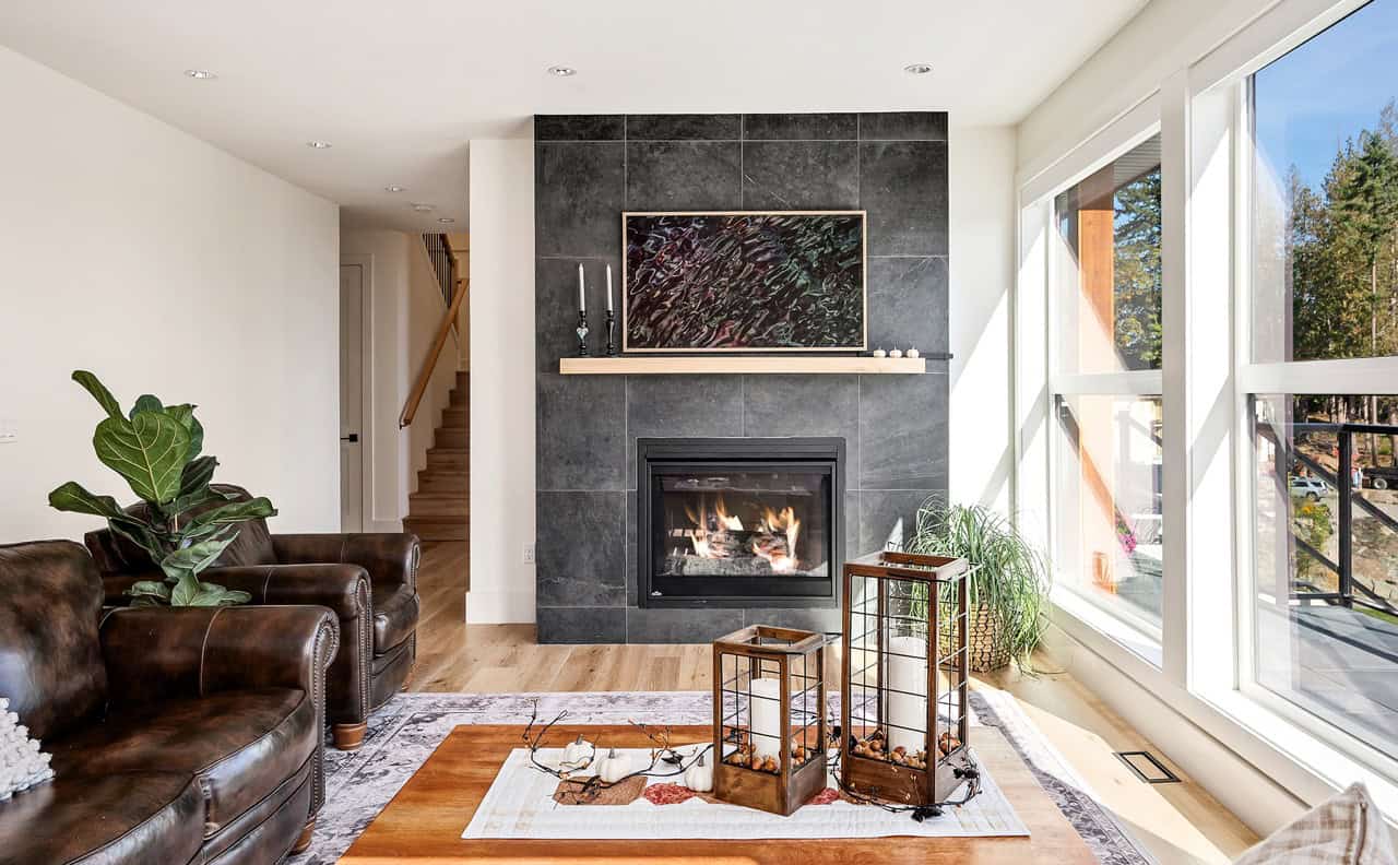 Elegant living room with dark slate fireplace, large windows, and leather seating.
