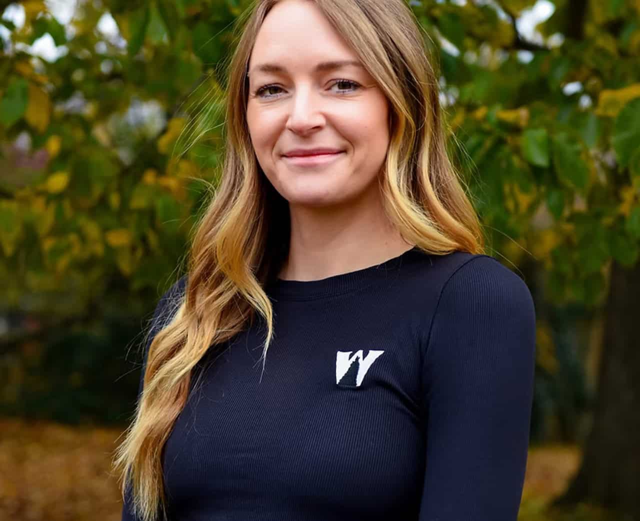 Portrait of a team member wearing navy shirt with White Wolf Homes logo in outdoor setting.