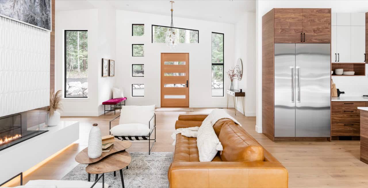 Interior living room with modern fireplace, leather sofa, and bright open kitchen.
