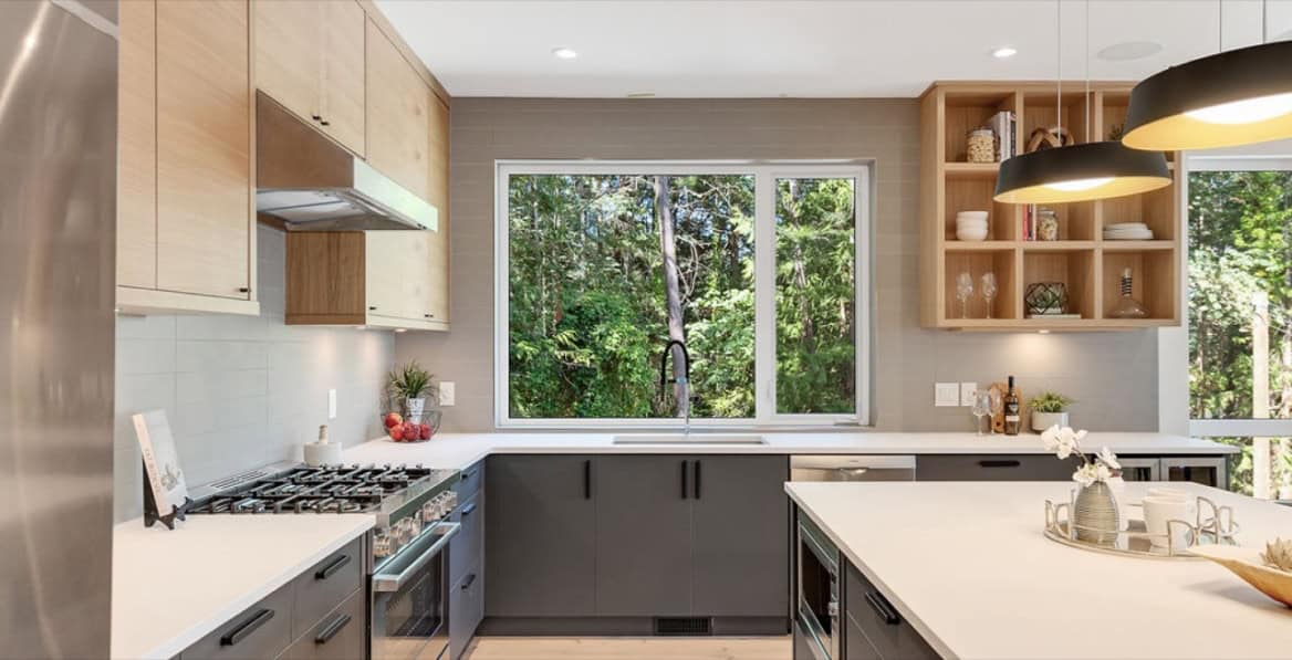 Modern kitchen with large window, grey cabinets, and island at Baylight project.