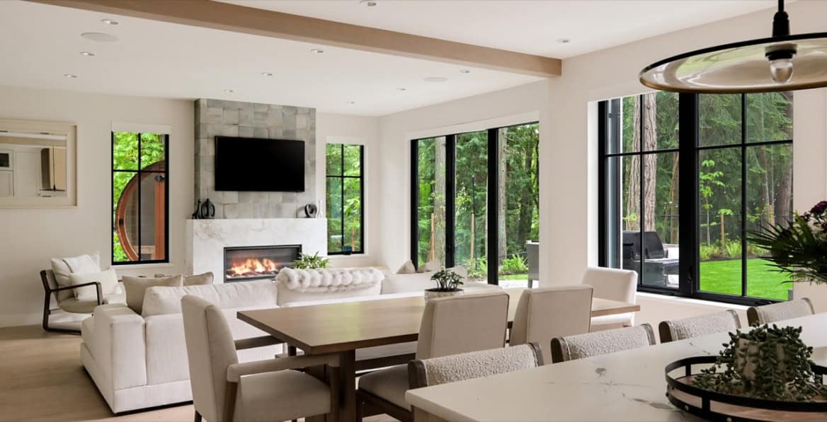 Modern open-concept living room with fireplace, large windows and neutral furnishings in Victoria BC.