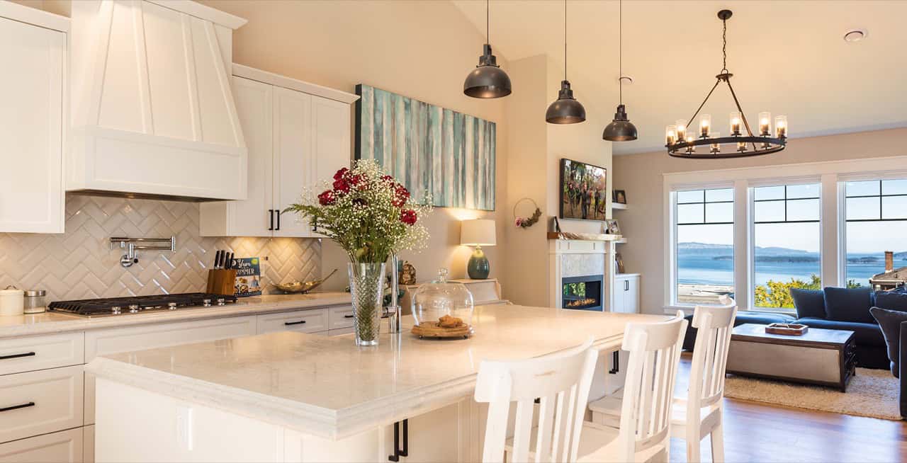 Modern kitchen featuring white cabinets, marble island, pendant lights and a coastal Victoria view.