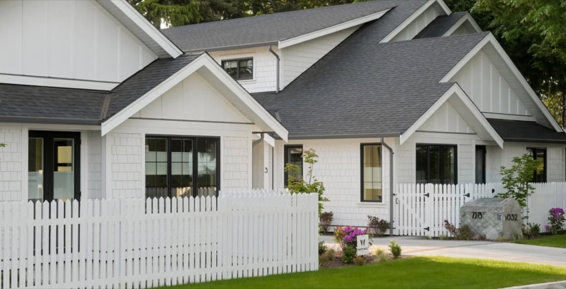 Victoria BC custom home exterior with white siding, grey roof, and white picket fence.