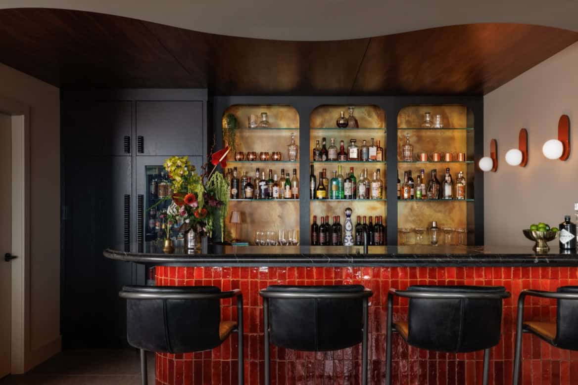 Victorian bar interior with red tiled counter and leather bar stools.