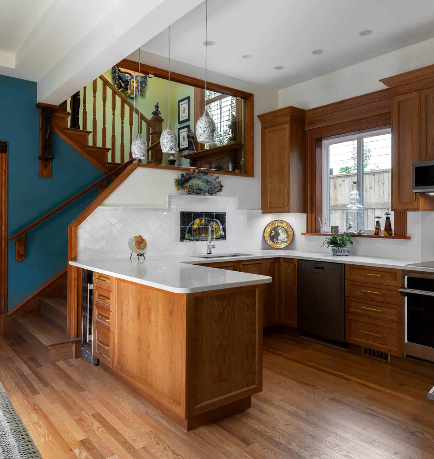 Open-concept kitchen with wood cabinetry, island, and staircase in a modern home by White Wolf Homes.