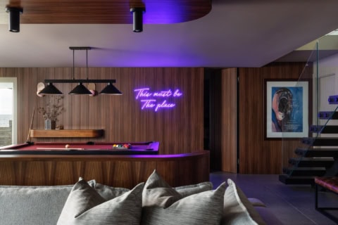 Modern home bar with neon sign, purple lighting, and pool table in a stylish Victoria BC residence.