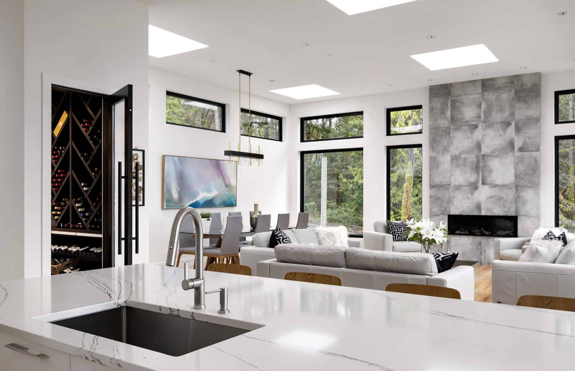 Open-concept living area with white furniture and large windows in a modern home.