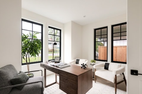 Modern home office with large windows, wooden desk, and white seating in Victoria BC.