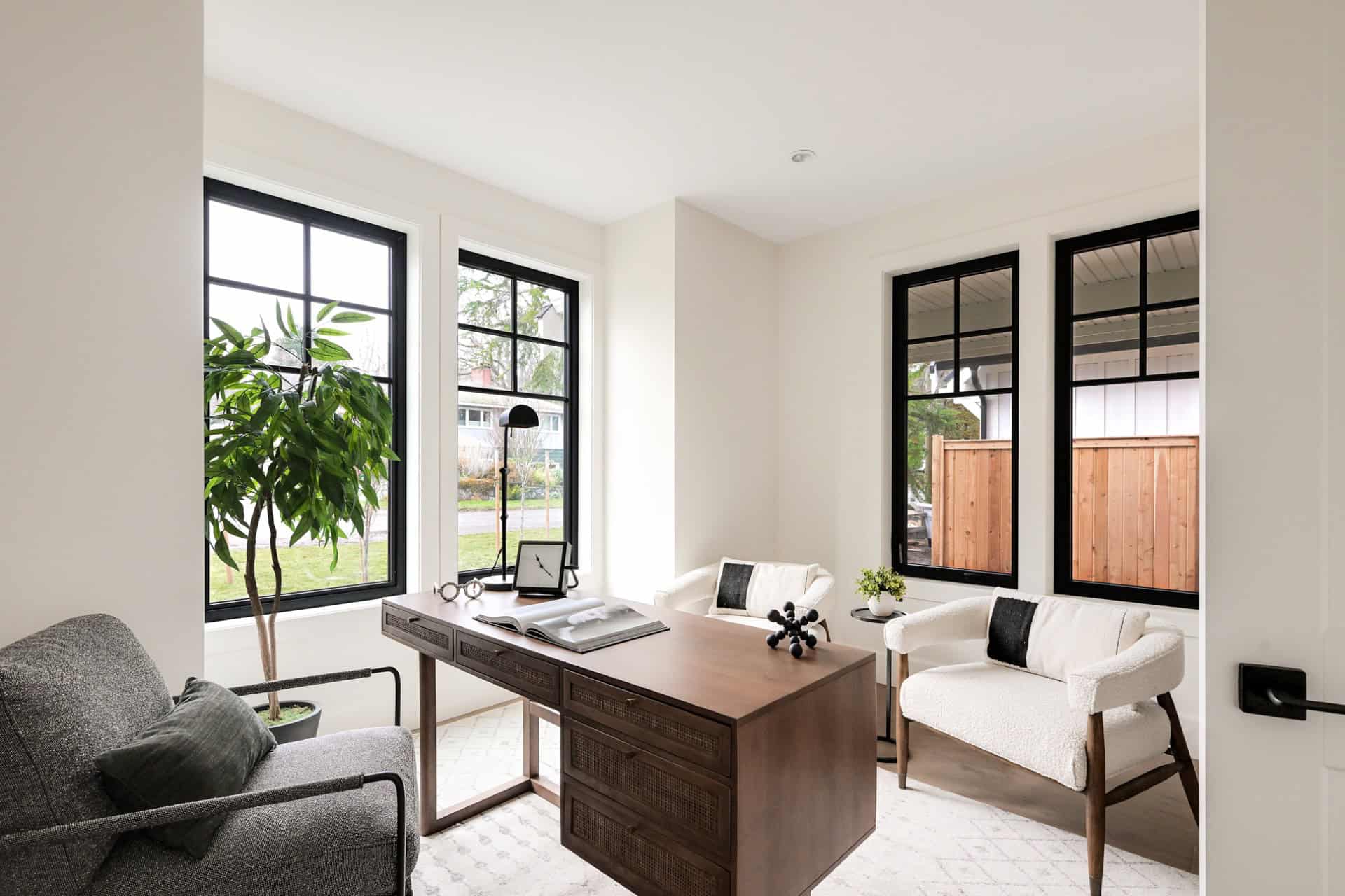 Modern home office with large windows, wooden desk, and white seating in Victoria BC.