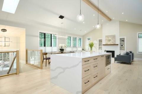 Open-concept kitchen with island, light wood flooring, and modern fixtures in a bright home.