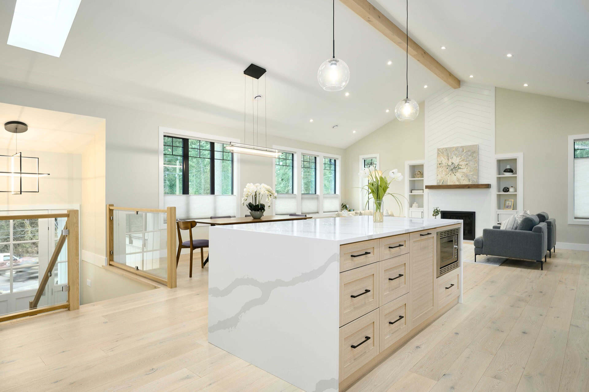Open-concept kitchen with island, light wood flooring, and modern fixtures in a bright home.