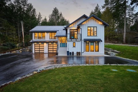 White Wolf Homes modern custom home in Victoria BC with metal roof and large windows at dusk.