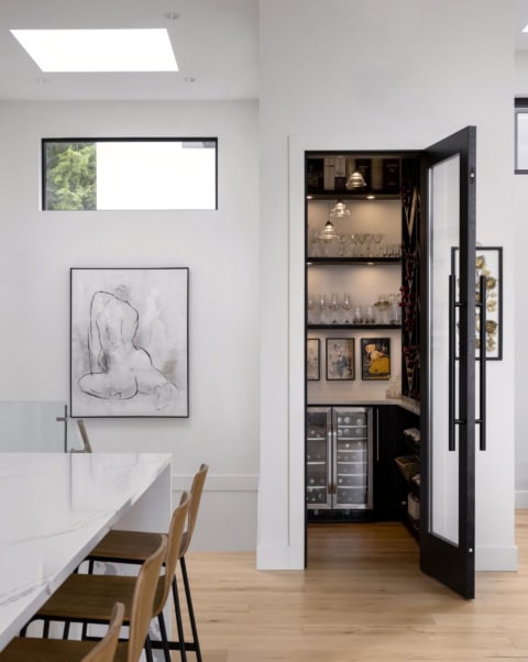 Interior view of a modern kitchen and dining area with a black glass door to a wine cabinet, light,.