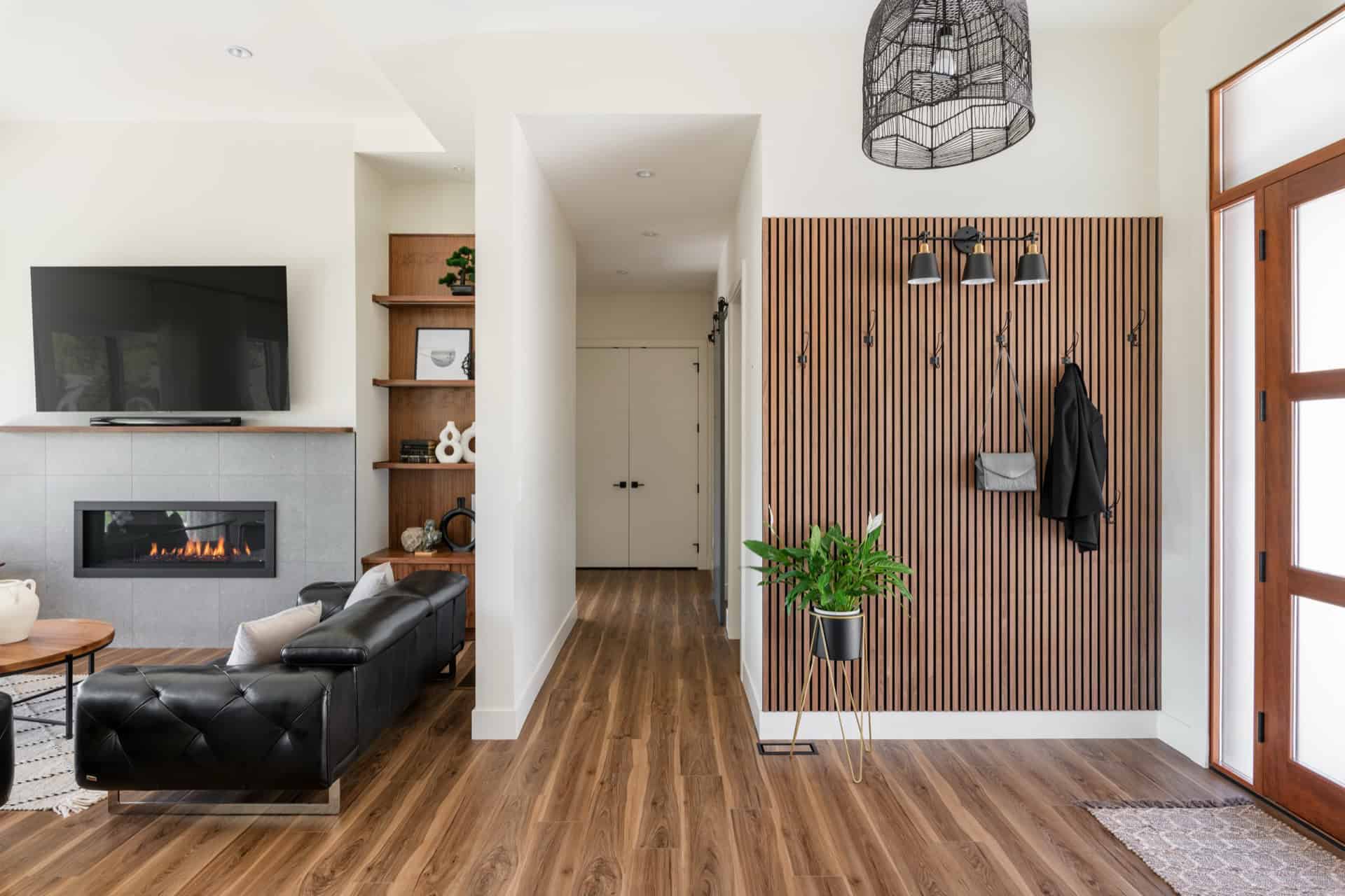 Modern living room with fireplace, wood flooring, and contemporary decor by White Wolf Homes.