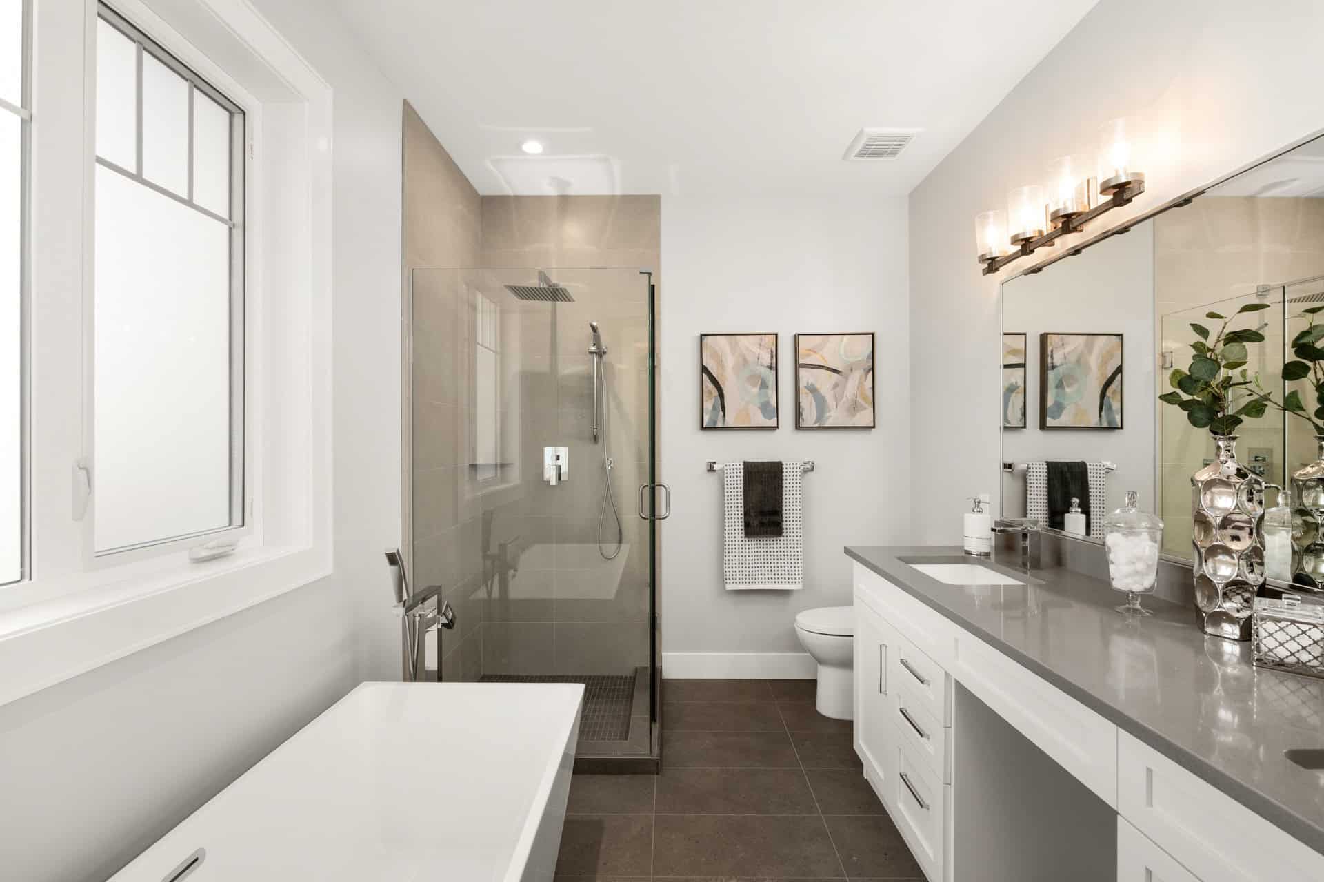 Modern bathroom design with glass shower, double vanity and neutral tones.