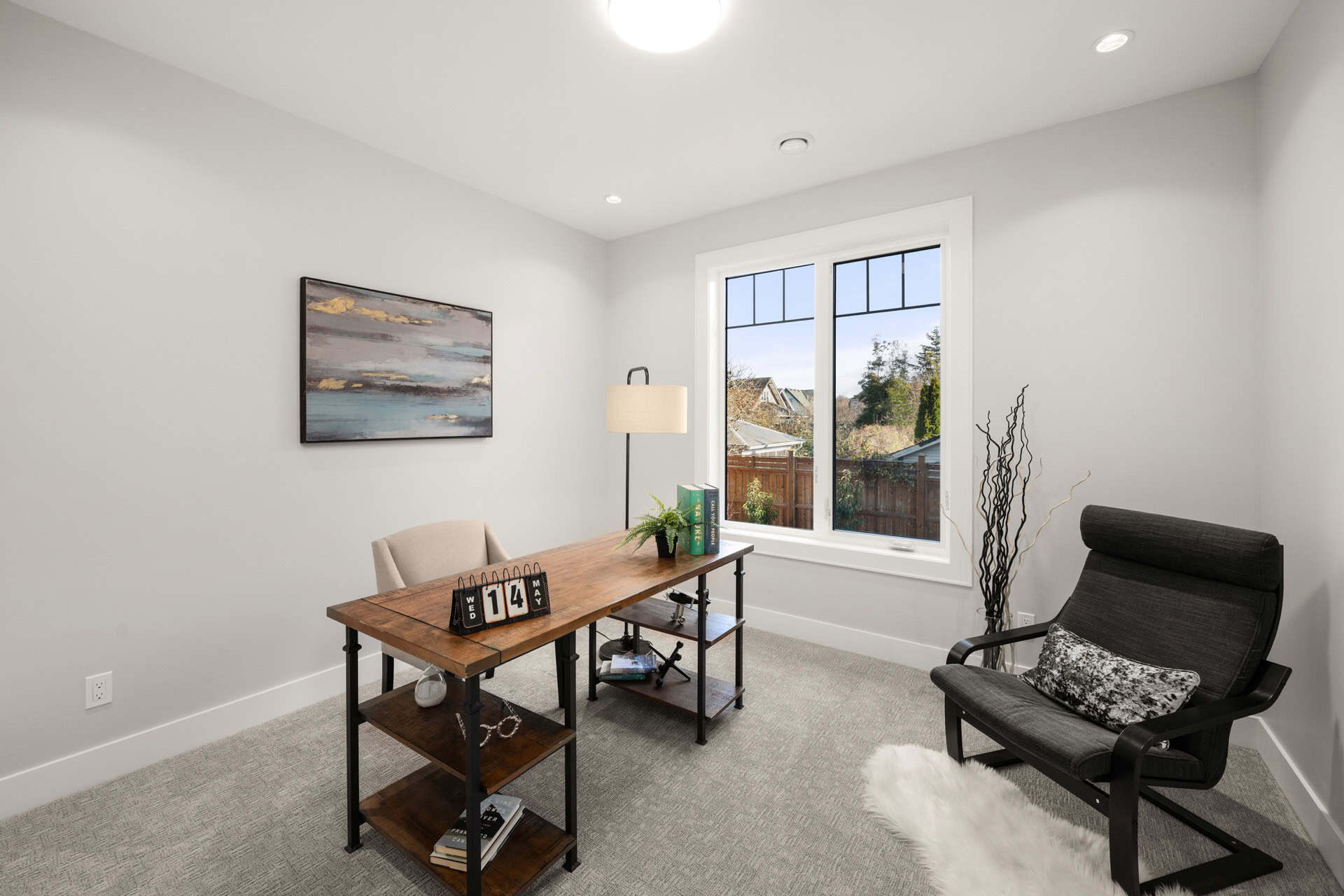 Modern home office with desk, chair, and view of neighborhood through window.