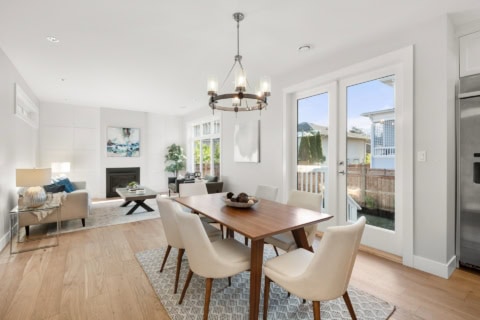 Bright open-concept living and dining area with a wooden table and modern chairs.