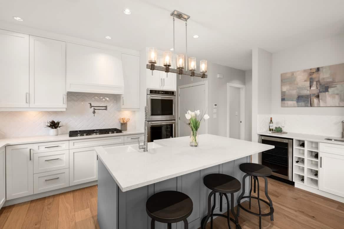 Bright white modern kitchen with island and pendant lighting in Victoria BC home.
