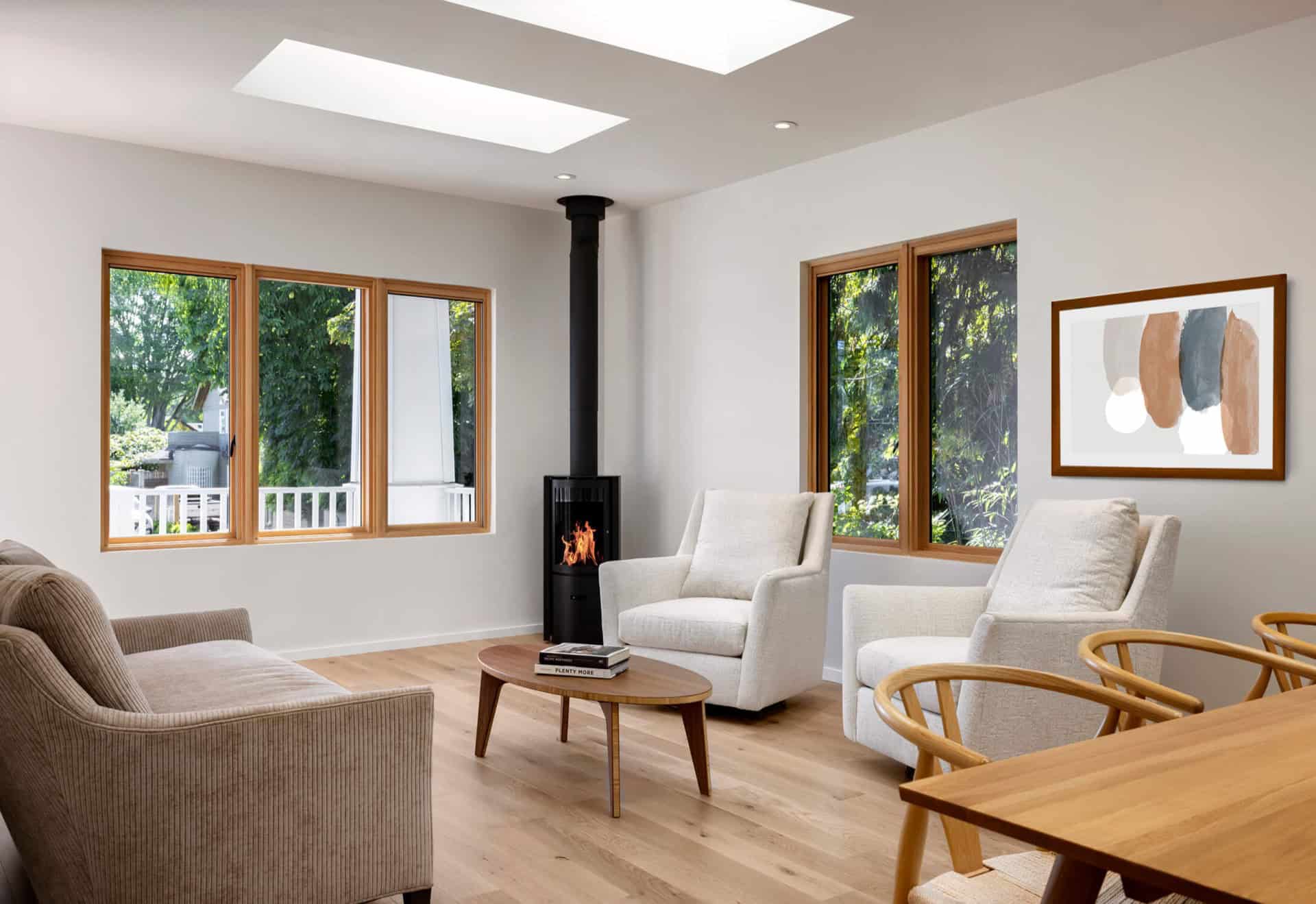 Bright living room with large windows, modern wood furniture, and a wood-burning stove in Victoria,室.