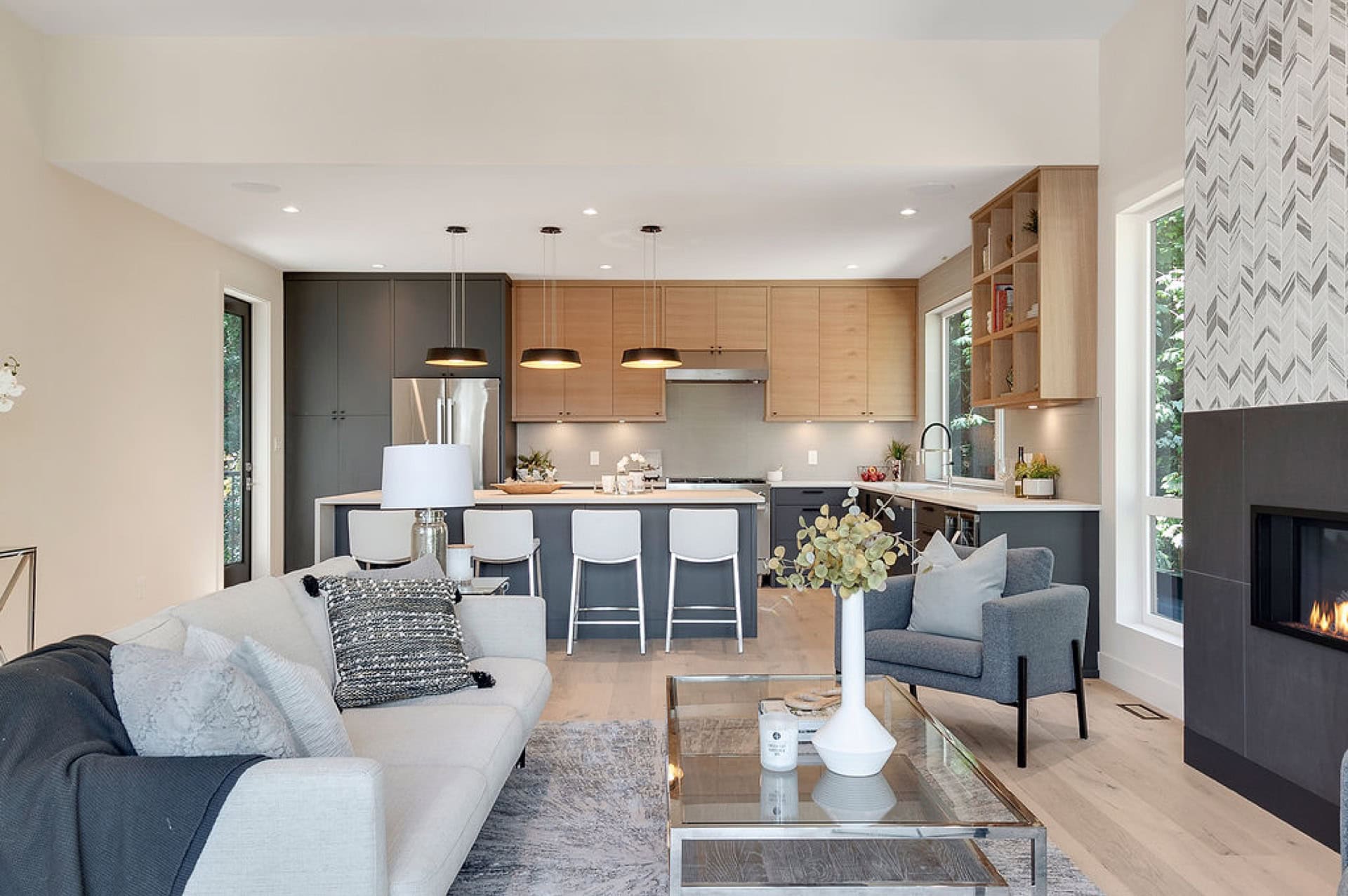 Open-concept living area with kitchen island, grey and wood tones, and fireplace in a canvassed Canv.