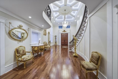 Elegant Victorian-inspired foyer with curved staircase, ornate chairs, and chandelier in Parkwood, a.