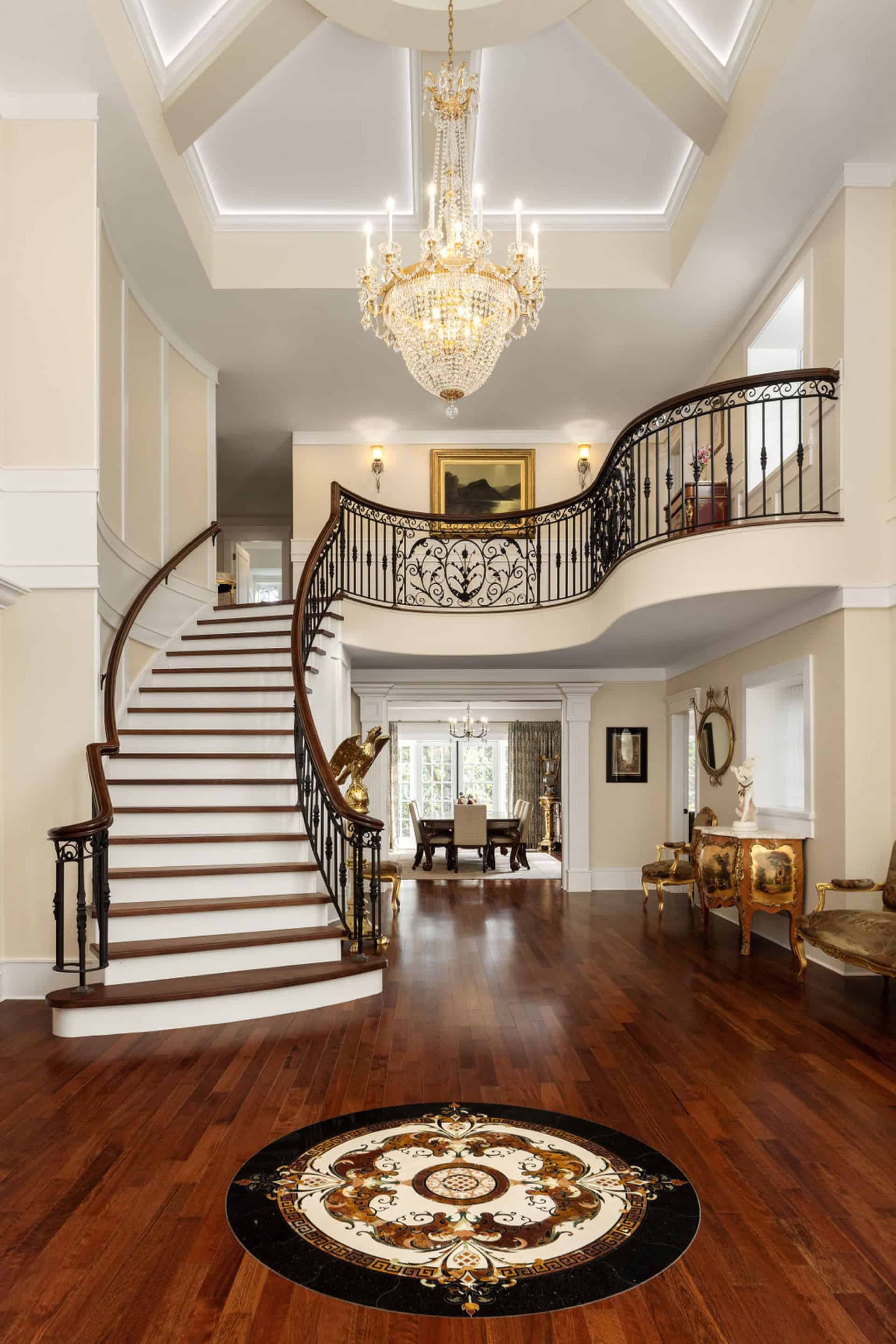 Elegant grand foyer with sweeping curved staircase and chandelier in a luxurious Victorian-style two.