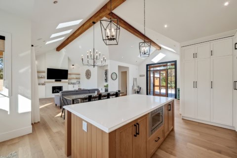Open-concept kitchen with oversized island, vaulted ceiling, and modern lighting in a White Wolf Hom.