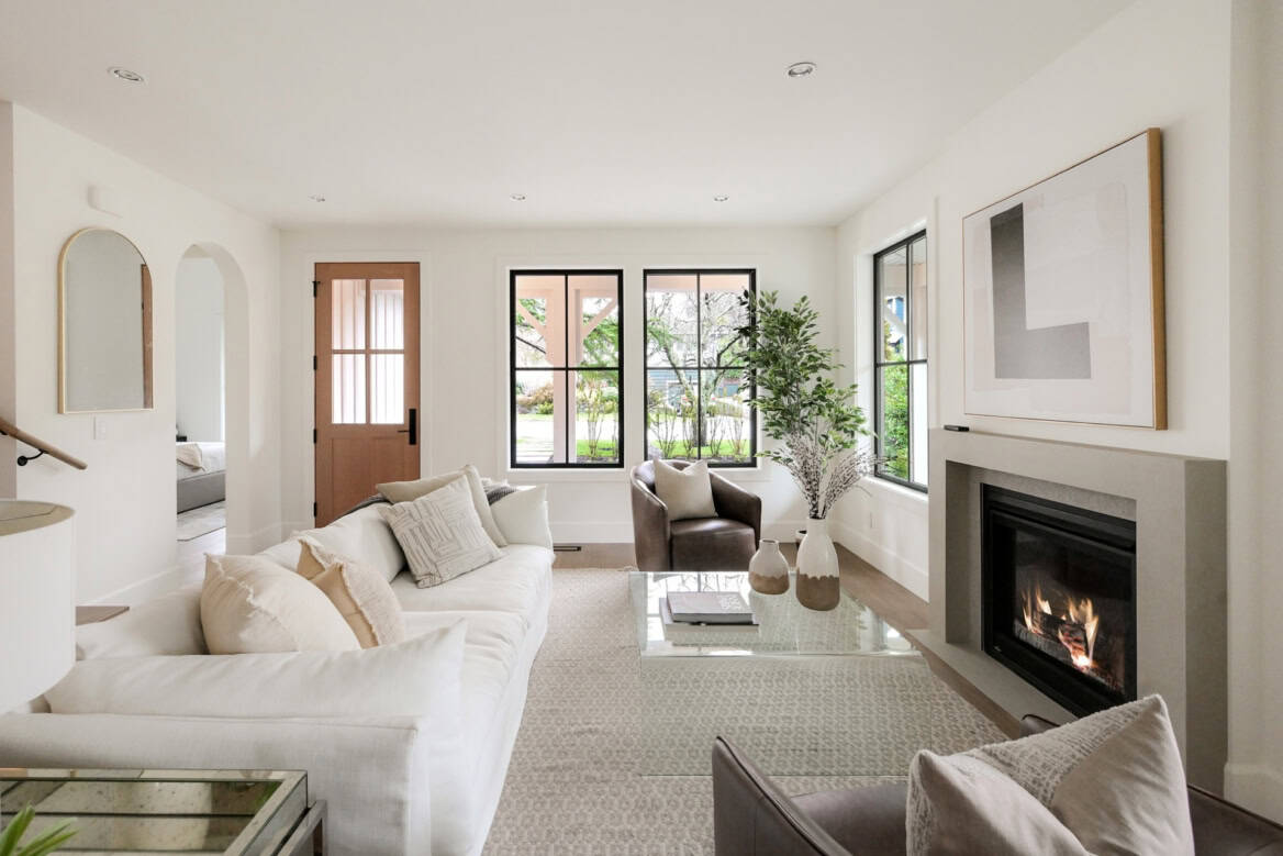 Modern living room with white sofa, fireplace, and large windows in a Victoria BC home.