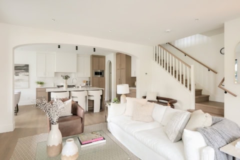 Living area of a modern home with white and neutral tones, open layout, and staircase in a Victoria,.