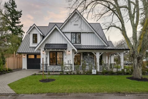 Custom Victoria BC home with white siding, gray roof, stone accents, front porch, and landscapedyard.