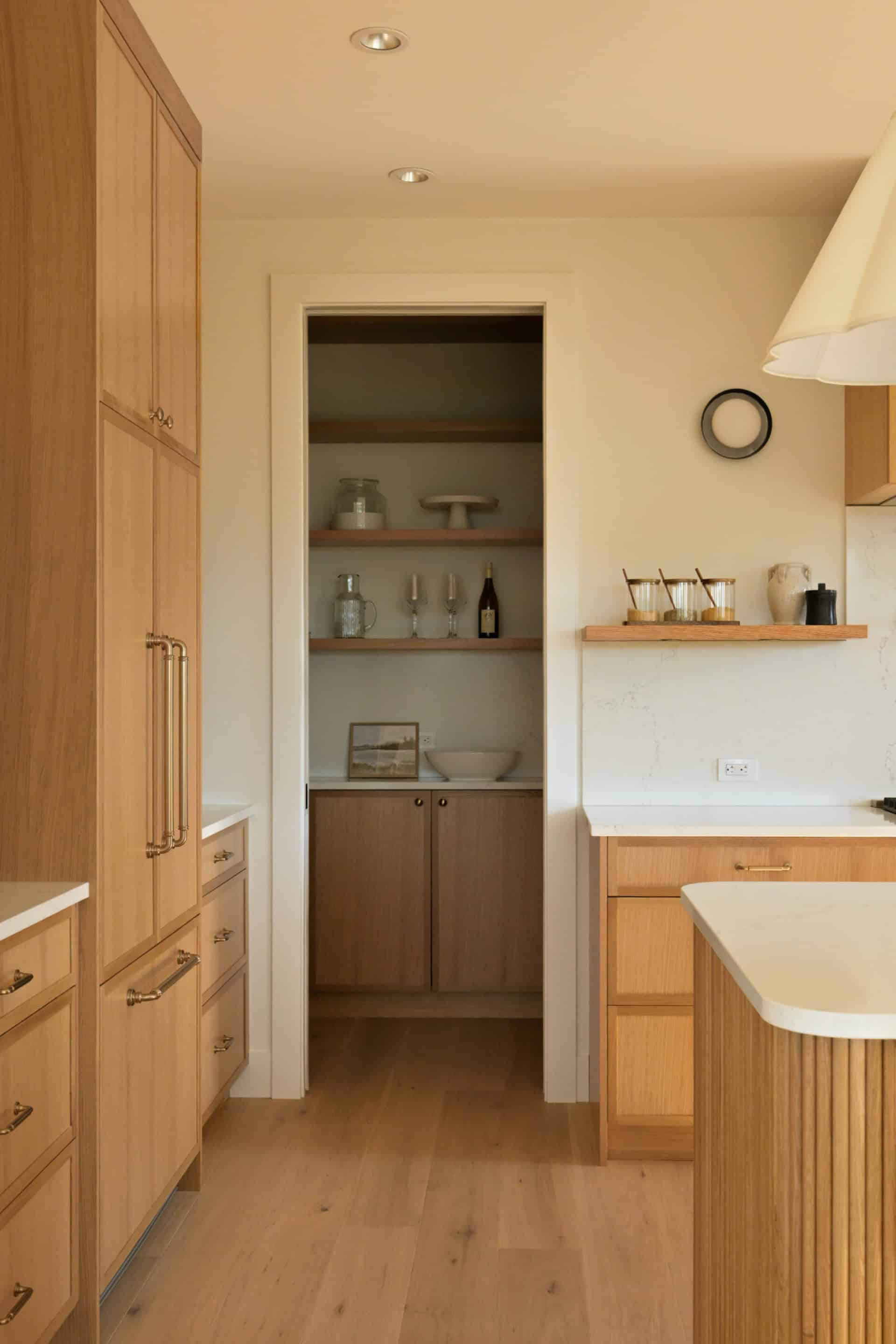 Bright kitchen with wooden cabinets, open pantry shelves, and island in Victoria BC home.