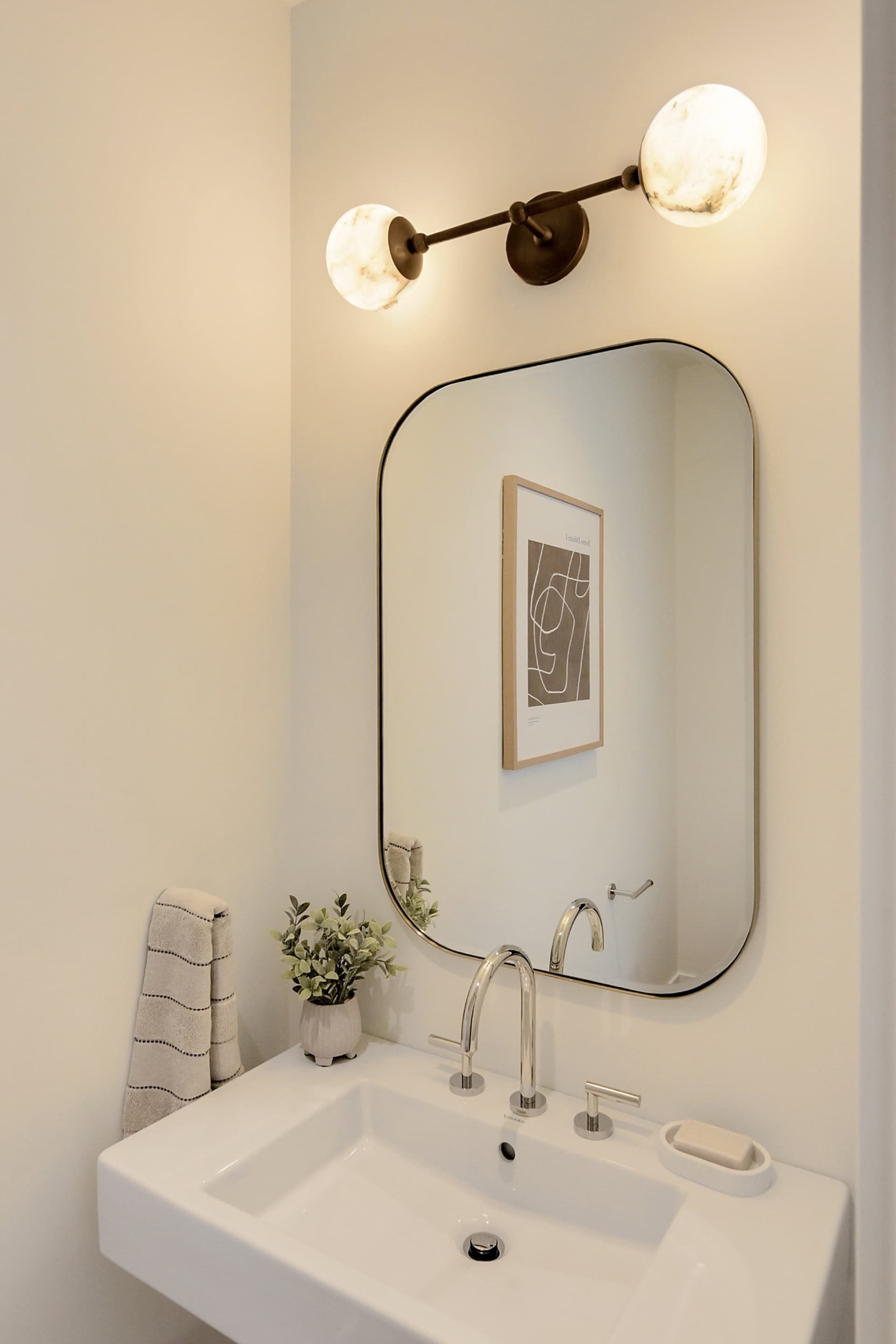 Modern bathroom vanity with oval mirror and wall lighting in Victoria BC home.
