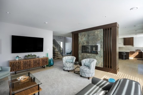 Victoria BC custom home living room with modern fireplace divider and seating area.