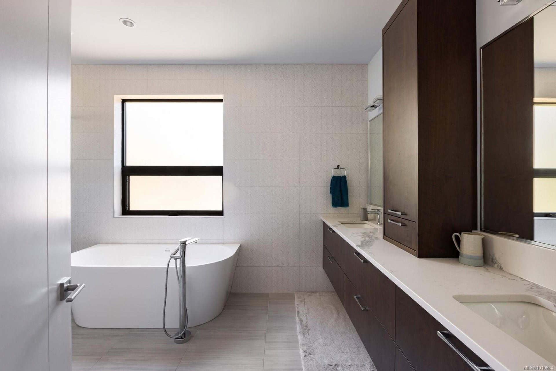 Modern bathroom with freestanding tub, double vanity and dark wood cabinets.