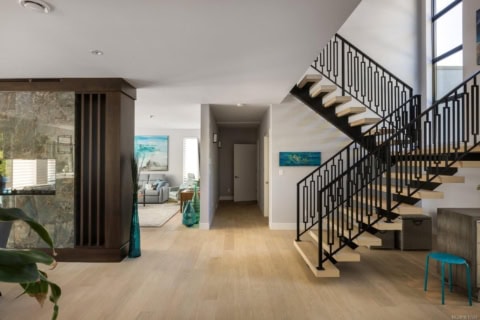 Bright open foyer with wooden stairs and modern decor in Haven by White Wolf Homes.