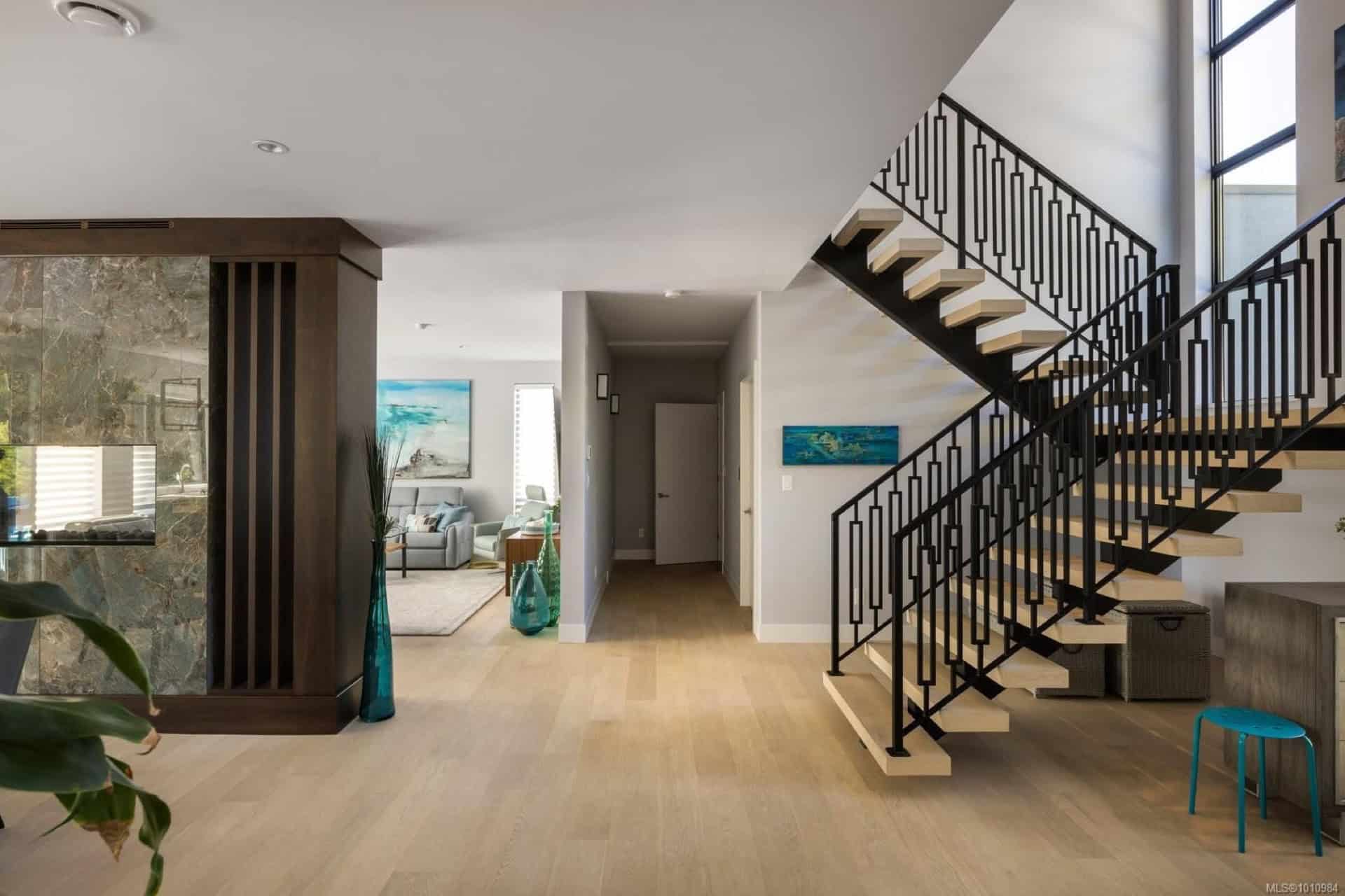 Bright open foyer with wooden stairs and modern decor in Haven by White Wolf Homes.