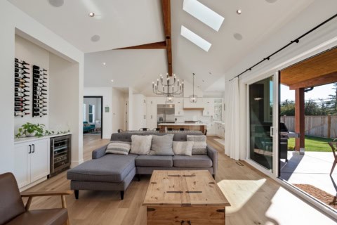 Bright open-concept living room with large floor-to-ceiling windows and a wooden beam ceiling.