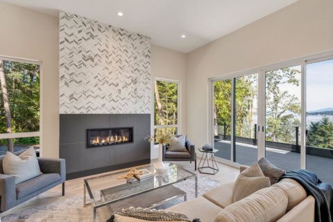 Open living room with modern fireplace and large windows offering ocean views.