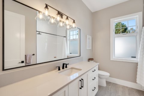 Bright modern bathroom with double vanity, large mirror and window.