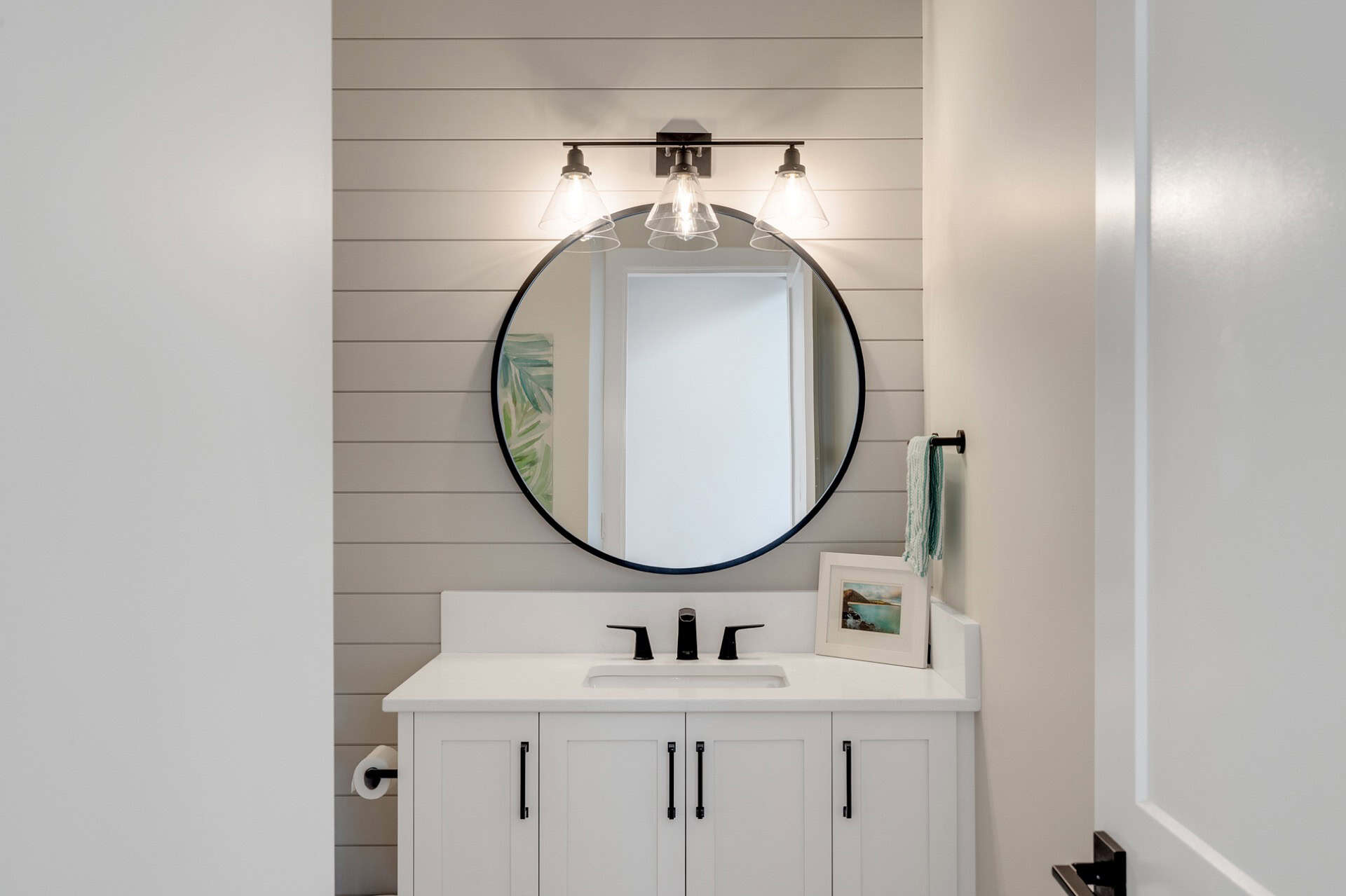 White Wolf Homes bathroom vanity with round mirror and shaker cabinets.