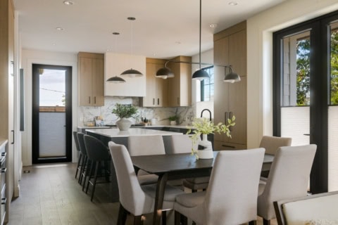 Modern kitchen with island, pendant lights, and dining area in Cedar & Stone project by White Wolf H.