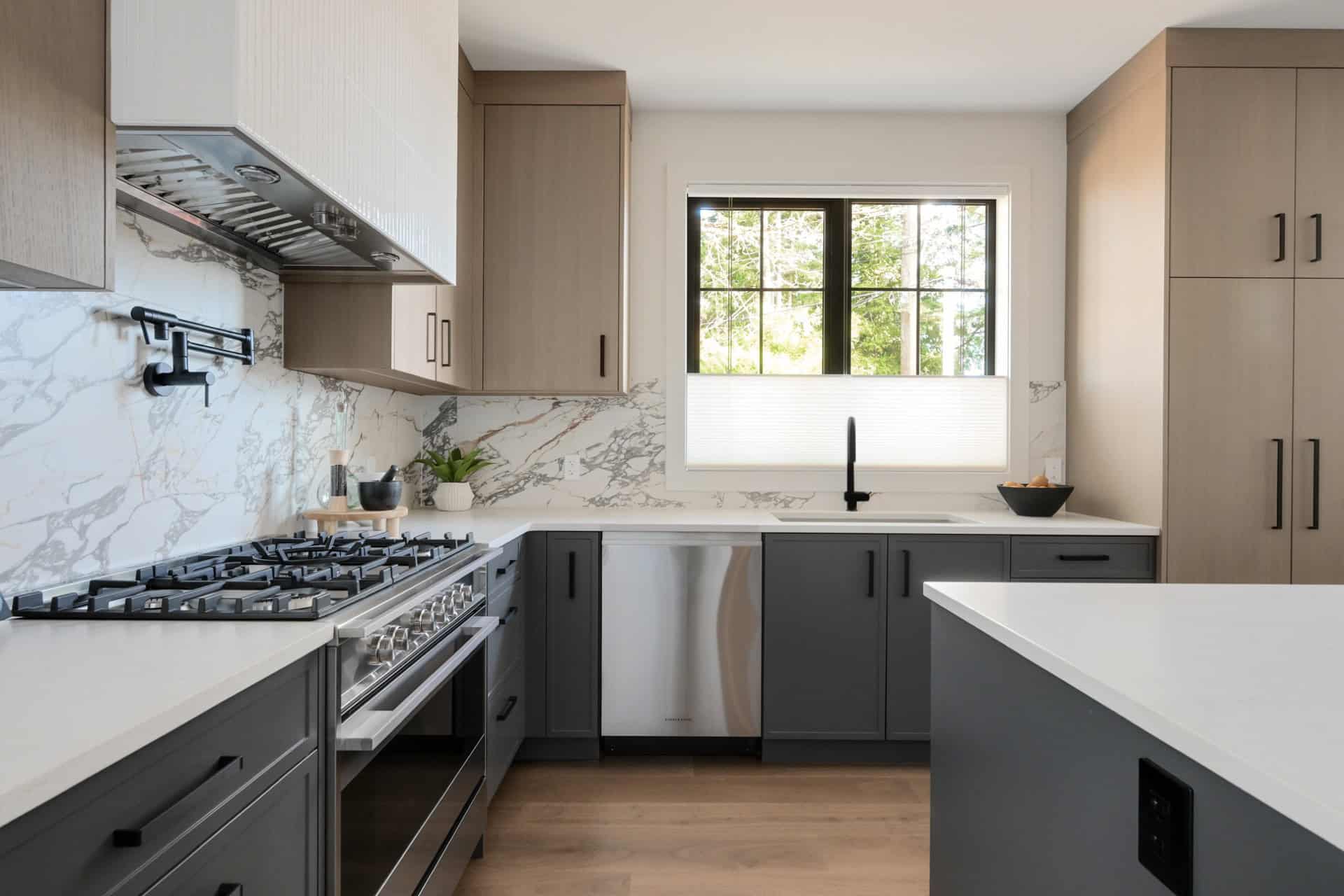 Modern kitchen by White Wolf Homes with marble backsplash, grey cabinetry, and stainless steel chef".